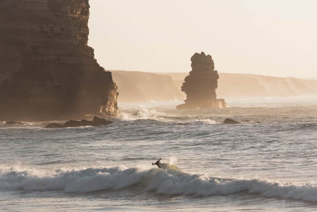 Surfer in arrifana beach, located in southwest portugal, in aljezur along the rota vicentina trail